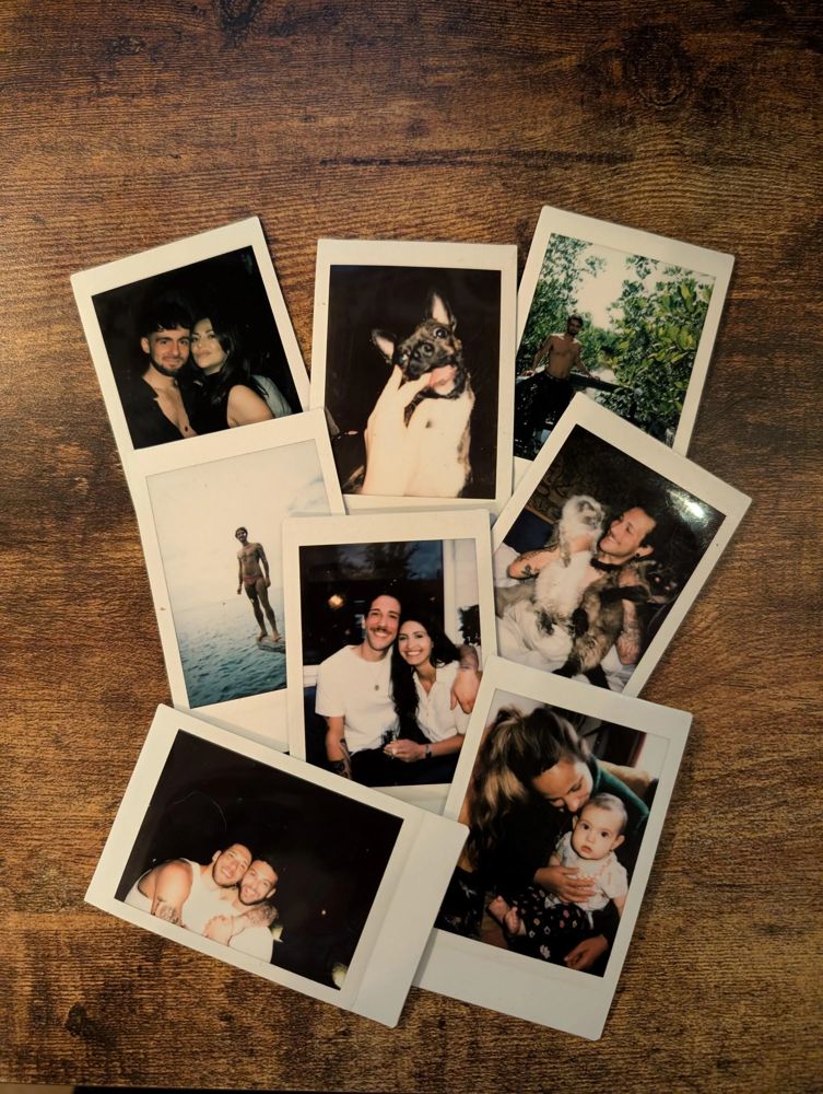 a pile of instax mini prints on a wooden table